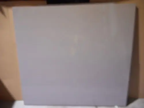 Graue Platte auf flachem Untergrund, teils reflektierend. Hintergrund unscharf. Produkt von Remeha, möglicherweise Teil eines Geräts oder Möbelstücks.